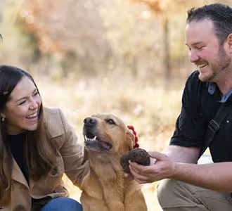 Image of a woman and a man patting a truffle dog after finding a truffle.
